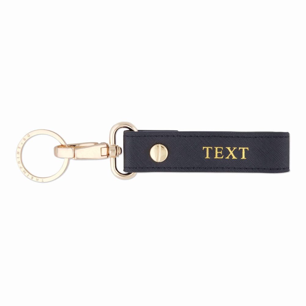Saffiano keychain in black and with gold text